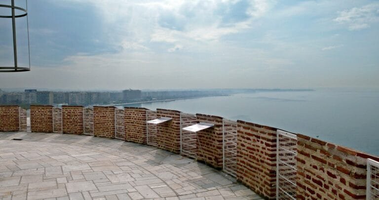 Balcony of the White Tower with brick battlements and metal signs overlooking the Thessaloniki waterfront and sea