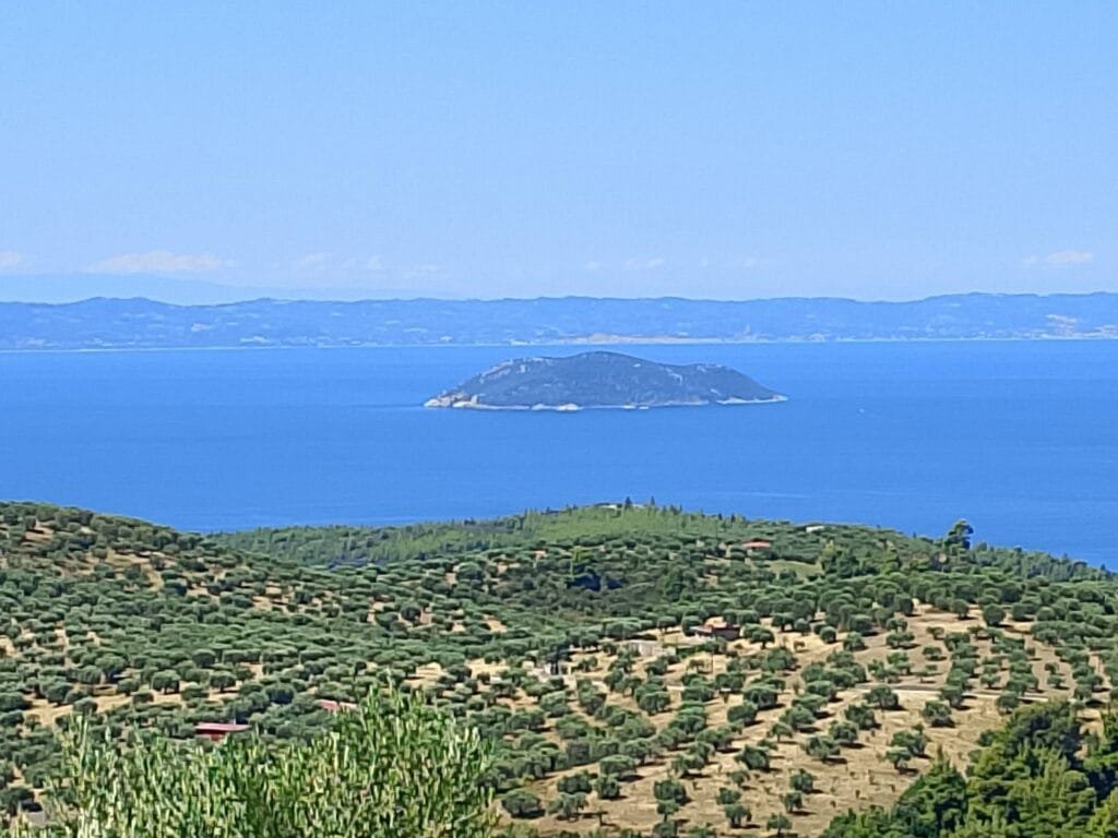 Panoramic view from Parthenon village over hillside olive groves to the Aegean Sea and a small island