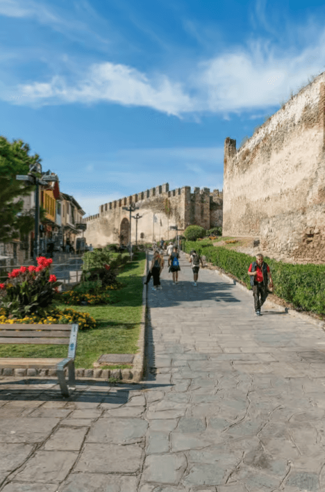 Tourists walking along a stone path beside the ancient Byzantine walls of Thessaloniki