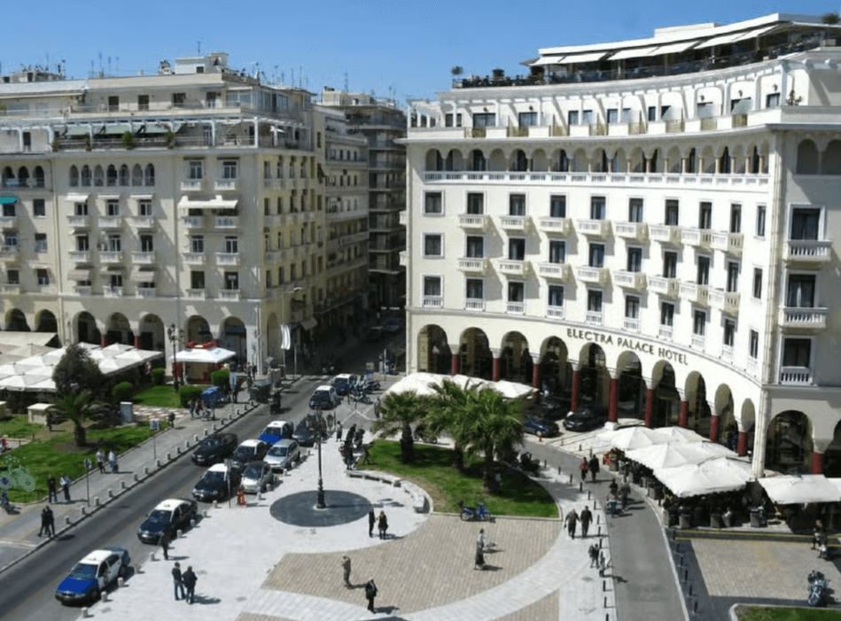 Aristotelous Square in Thessaloniki with neoclassical buildings, arched walkways, and people in the plaza