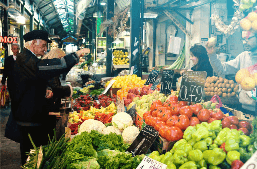 Bustling market stall in Thessaloniki with vibrant displays of fresh tomatoes, peppers, and cauliflower