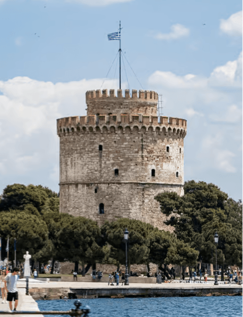 The White Tower of Thessaloniki on the waterfront with a Greek flag flying at the top
