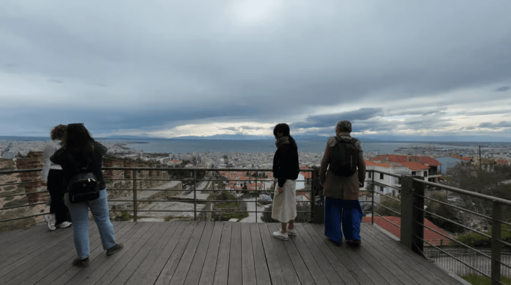 People on a wooden observation deck in Ano Poli overlooking the city of Thessaloniki and the sea