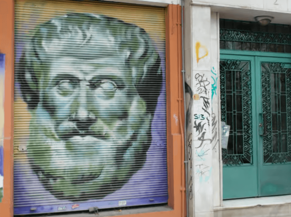 Mural of a classical bust painted on a metal storefront shutter in a Thessaloniki alley