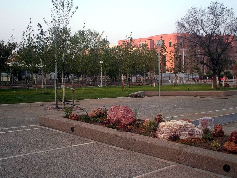 The Garden of Music featuring a paved area, a grassy lawn with young trees, and the Concert Hall in the background