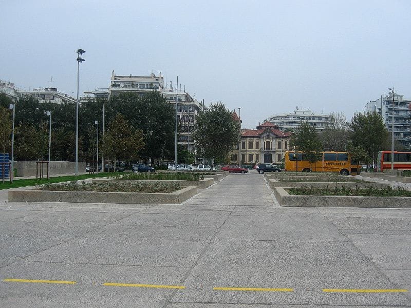 Raised flower beds and paved walkways in the Garden of Remembrance, with city buildings in the distance