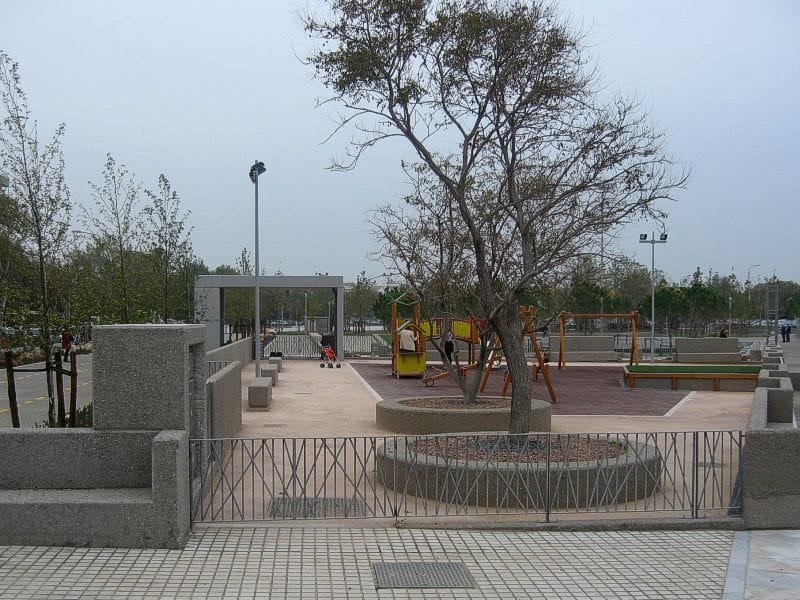 Children's playground with swings and climbing frames in the Garden of Music, surrounded by trees and paved paths
