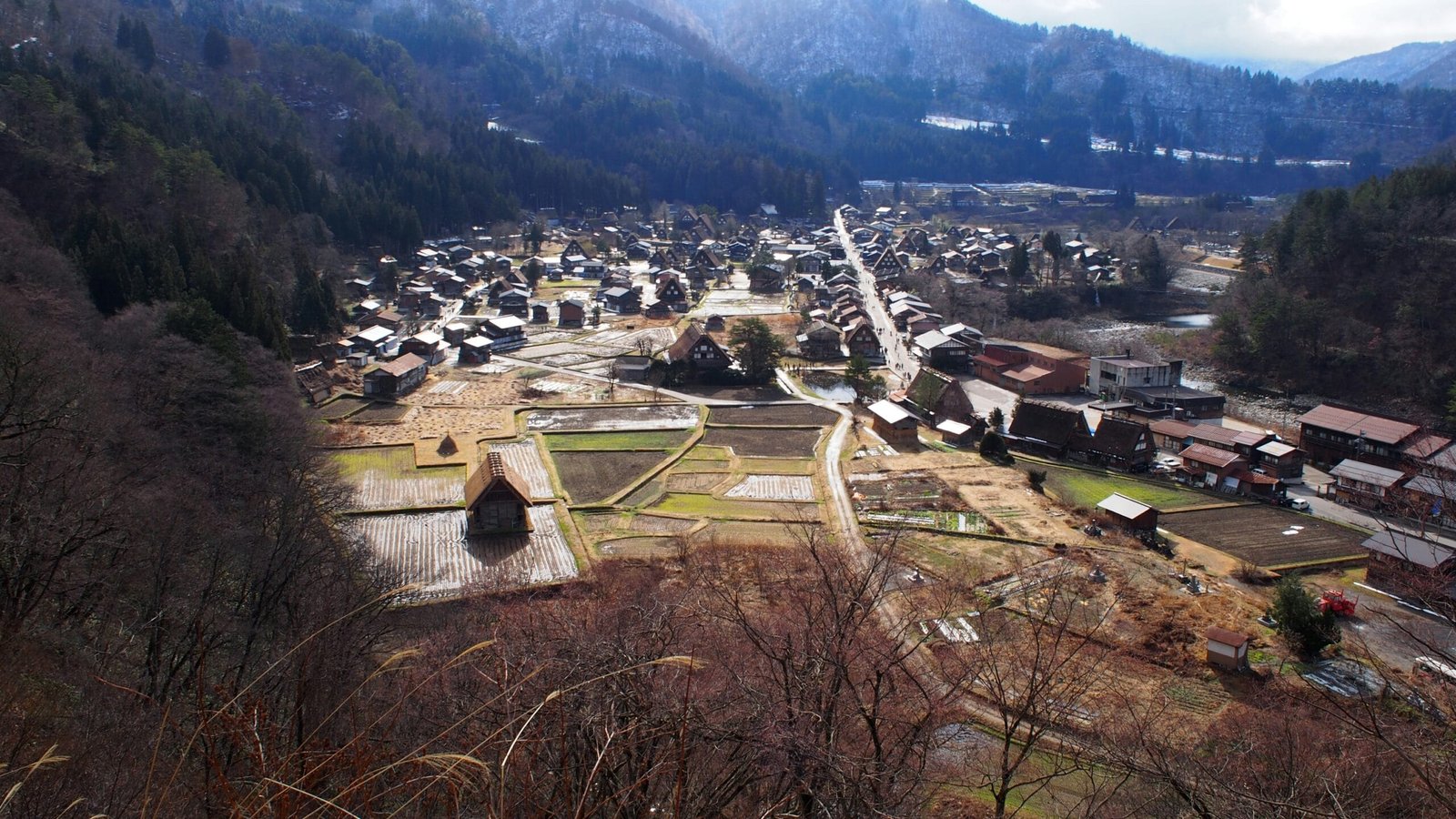 Panoramic view of a mountain village with traditional steep-roofed houses and agricultural fields