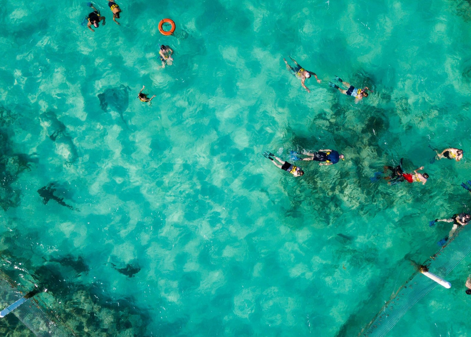Aerial view of people snorkeling in the crystal-clear turquoise waters of Blue Lake